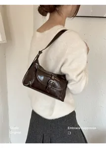 Detailed shot of a shiny dark brown underarm bag with a buckle pocket decoration