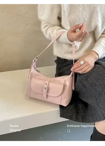 Close-up of a stylish pink underarm bag held by a model in a minimal setting.