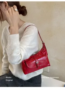 Fashionable red glossy leather underarm shoulder bag for women shown on a model
