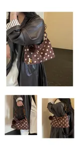 Detailed view of brown polka dot shoulder bag with wooden bead handle and fur pom-pom