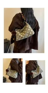 Side view of green suede polka dot shoulder bag with wooden bead strap and pom-pom charm