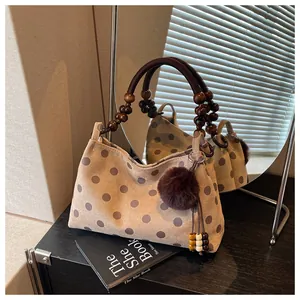 Detail of stylish polka dot bucket bag featuring unique wooden bead handle and fur pom-pom