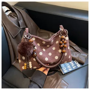 Close-up of a brown polka dot bucket bag featuring unique wooden bead handles and charm