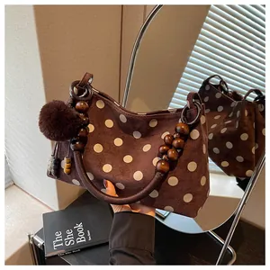 Detail of brown polka-dot bucket bag with vintage wooden bead handle and a pom-pom