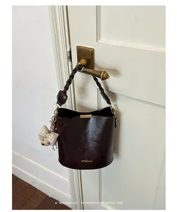 Detail of a brown retro bucket bag with a woven handle hanging on a door handle.