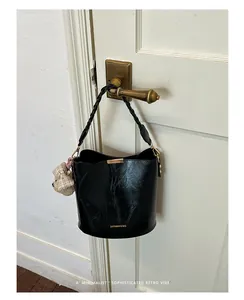 Black leather bucket bag hanging on a vintage door handle showing a minimalist retro style