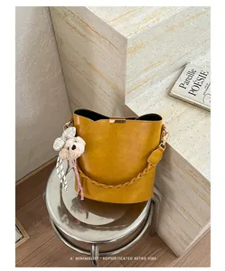 Detail view of mustard yellow leather bucket bag with teddy bear charm on silver stool