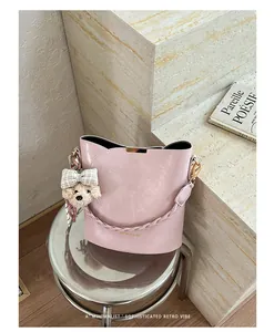 Close-up of stylish pink bucket handbag with a cute teddy bear charm on a metal stool