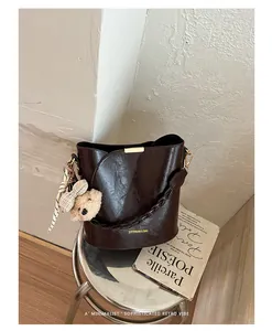 Elegant dark brown leather bucket bag displayed on a stool with retro book props.