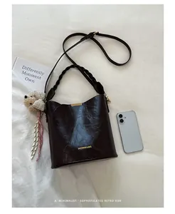 Chic dark brown leather bucket bag with braided handle shown with lifestyle accessories.