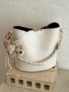 Premium white bucket bag for women featuring a braided strap and cute bear charm