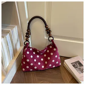 Detail of a vintage burgundy polka dot shoulder bag with stylish wooden bead handles.