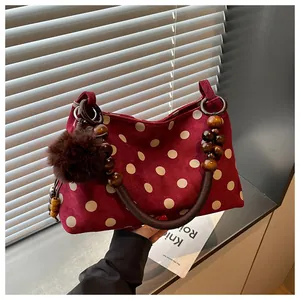Close-up detail of wine red polka dot suede handbag featuring unique wooden bead handle