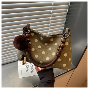 Close-up of olive green polka dot bucket bag with wooden beads and pom-pom charm.