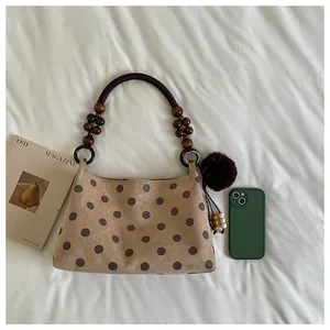 Flat lay of stylish khaki polka dot bucket bag with beaded handle and faux fur charm