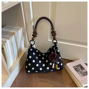 Close-up of black polka dot bucket bag with wooden bead handle and fur charm