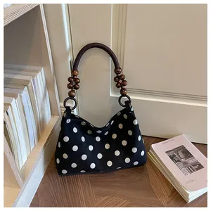 Vintage polka dot shoulder bag with unique wooden bead handle in lifestyle setting