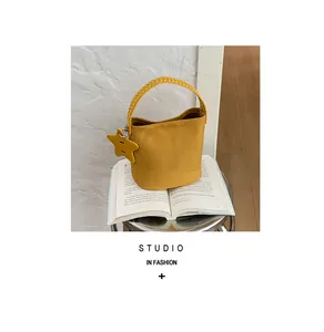 Sac seau jaune de haute qualité avec détail de pendentif étoile posé sur un livre ouvert