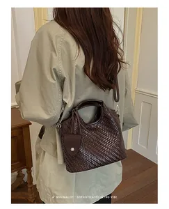 Sofisticado bolso cubo tejido marrón oscuro para viajes diarios con estilo y uso cruzado.