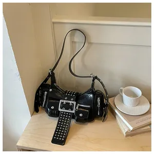 Zwarte retro schoudertas van olieleer met zilveren studs en gesp op een houten bureau