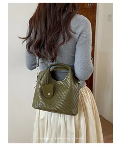 Detalle de bolso bandolera verde con textura tejida en modelo para un estilo retro.