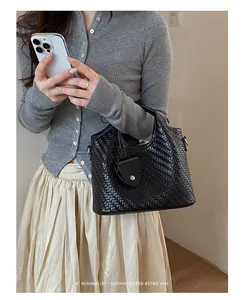 Elegante bolso bombonera tejido en negro para mujer combinado con un conjunto de punto gris