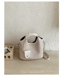 Vista detallada del bolso saco de tejido beige que muestra su textura y correa premium