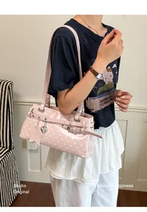 Close-up of stylish pink polka dot underarm shoulder bag with cute charms for women