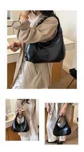 Lifestyle view of a large black vintage hobo bag with rivet details on model.