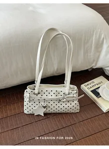 Stylish white polka dot underarm bag with decorative heart and star charms detail.