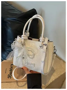 Elegante bolso de mano blanco trenzado con lazo de encaje y perlas decorativas