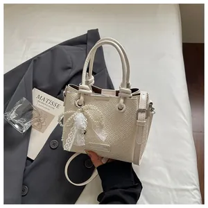 Elegante bolso de mano con textura tejida y dijes de perlas y encaje en escenario.