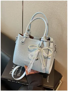 Detalle de bolso saco trenzado azul claro con lazo de perlas y encaje sofisticado
