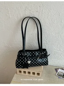 Detailed view of a black and white polka dot shoulder bag with stylish buckles