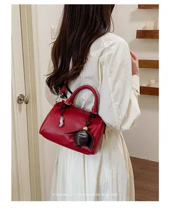Sac Boston rétro rouge élégant porté par un mannequin portant une robe blanche chic