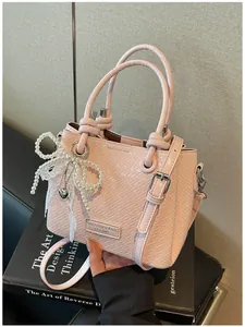 Elegante bolso tipo cubo rosa trenzado con un adorno de lazo de perlas y encaje fino