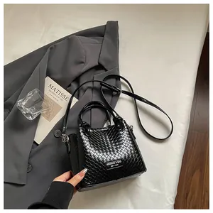 Elegante bolso de cubo negro con correa ajustable y asa superior de diseño tejido