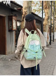 Rückansicht einer Frau mit einem leichten grün-blauen Wanderrucksack für Outdoor.