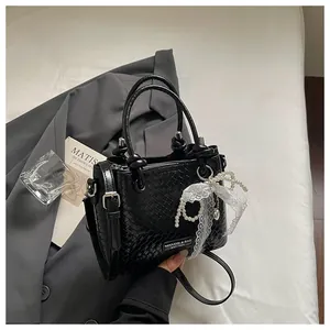 Bolso cubo pequeño negro trenzado con colgante decorativo de perlas y lazo de encaje