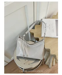 Borsa a spalla sottobraccio beige minimalista in un ambiente retrò di tendenza