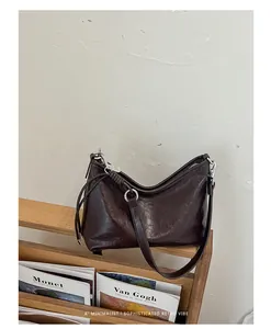 Borsa sottobraccio marrone scuro lucida su scaffale in legno, stile rétro minimalista