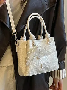 Bolso de cubo blanco con textura tejida, colgante de perlas y correa.