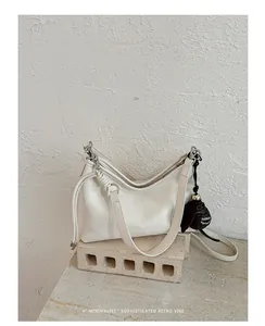 Elegante borsa sottobraccio minimalista in pelle bianca su un piedistallo di pietra