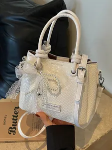 Elegante bolso saco trenzado blanco crema con amuleto de perlas y lazo de encaje fino