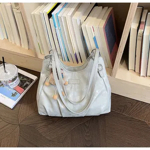 Bolso tote vintage gris con textura colocado frente a una estantería de libros acogedora