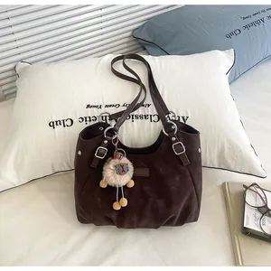Primer plano de bolso tote marrón oscuro vintage con colgante de oveja en escena real.