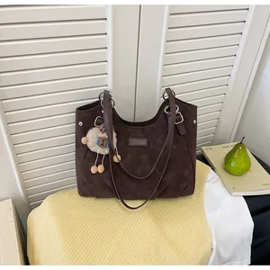 Primer plano de un bolso tote de ante marrón vintage con un lindo colgante de oveja de peluche
