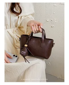 Gros plan d'un sac à main minimaliste marron foncé avec un charm élégant pour femme