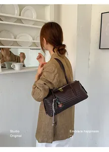 Detailed macro view of the dark brown woven texture shoulder bag on a female model.