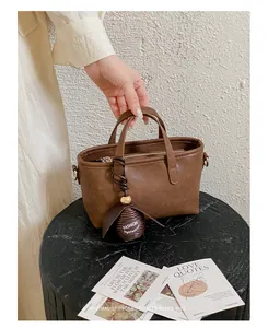 Vue détaillée d'un sac cabas marron rétro doté d'une breloque sphérique décorative